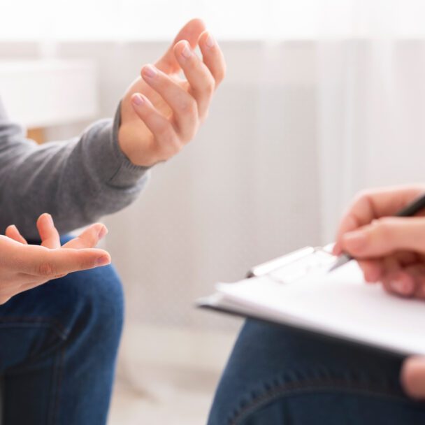 Psychotherapist writing notes, assessing patient's health and giving diagnosis to man sitting on couch during counseling session , panorama, free space